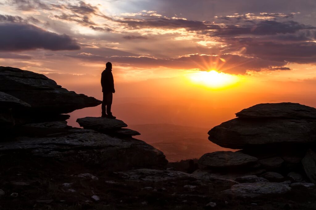 Mastering the First Impression: Your intriguing post title goes here A dramatic scene of a person standing on a rocky cliff during sunset.