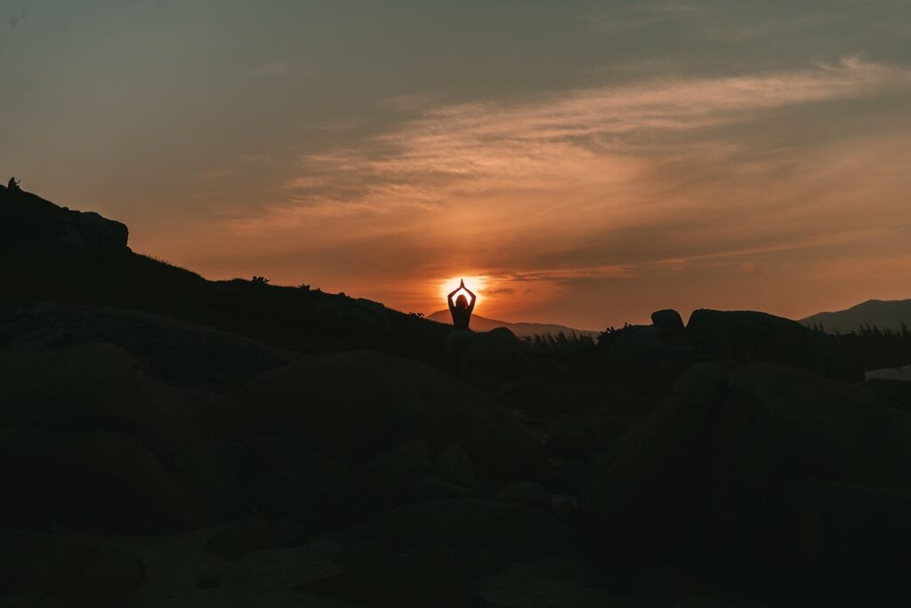 The Art of Drawing Readers In: Your attractive post title goes here A serene yoga silhouette against a sunset backdrop amidst rocky landscape.